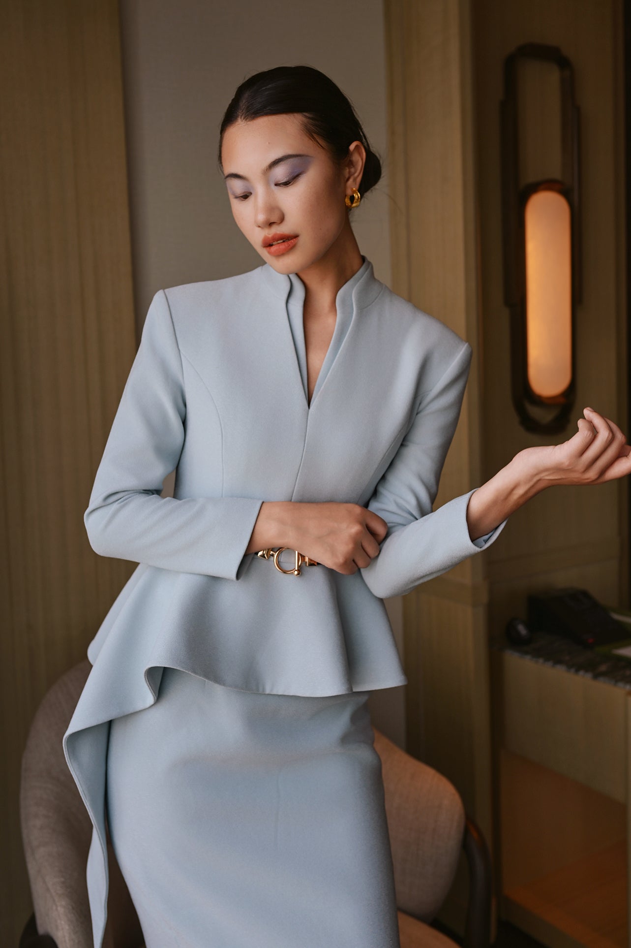 A comparison of three professional women modeling tailored power trouser suits featuring architectural split V-neck jackets with dramatic asymmetrical peplum hems and matching wide-leg trousers in crimson red, deep royal navy, and ice blue.