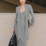 A beautiful professional model wearing an elegant grey pinstripe collarless blazer featuring a distinctive tie-front knot at the waist, styled with a crisp white collared shirt underneath for a modern corporate chic look.