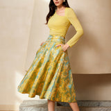 A professional woman wearing a sophisticated high-waisted A-line skirt, featuring a luxurious gold and teal wave pattern jacquard fabric and elegant full-skirt volume for a formal event.