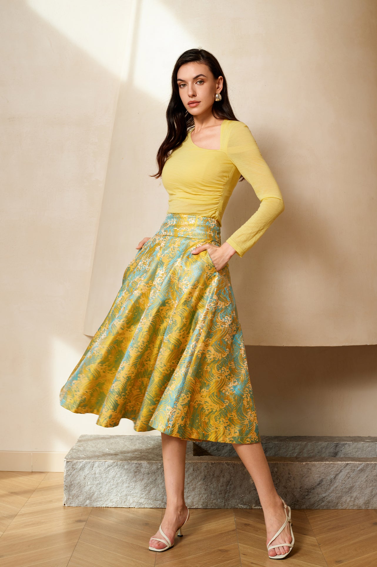 A professional woman wearing a sophisticated high-waisted A-line skirt, featuring a luxurious gold and teal wave pattern jacquard fabric and elegant full-skirt volume for a formal event.