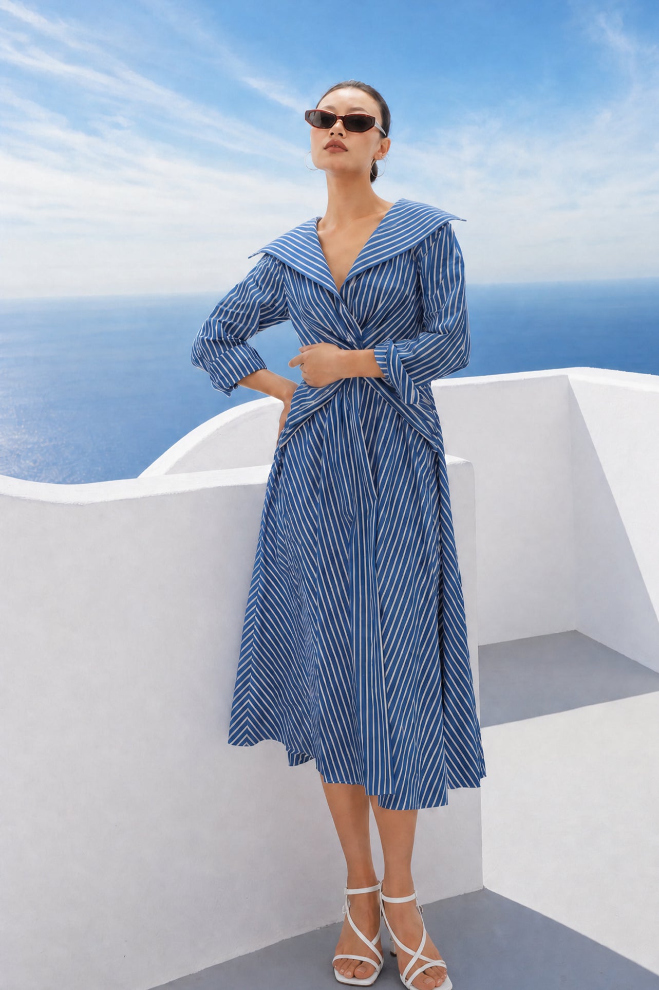 A style comparison of two elegant long-sleeve shirt maxi dresses featuring a unique twist knot waist design; the left showcasing a minimalist solid white dress with a popped collar, and the right featuring a classic blue and white vertical striped dress with a flattering A-line flare skirt.