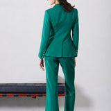 A professional woman wearing sophisticated emerald green high-waisted flare trousers, featuring a tailored slim fit through the hip and a stylish bootcut silhouette for an elegant office look.
