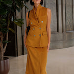 An elegant Asian woman posing in a luxurious camel wool two-piece suit featuring a sleeveless double-breasted longline vest cinched with a wide black belt, paired with a matching midi column skirt and black opera gloves.