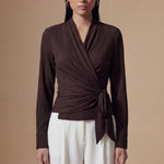 Two models presenting versatile textured wrap tops in cream and dark chocolate, featuring a slimming V-neck and elegant side-tie waist, styled with a tan pencil skirt and white high-waisted trousers.