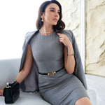 A professional woman wearing a sophisticated grey sleeveless sheath dress, featuring a tailored slim-fit silhouette and an elegant thin black belt with a gold buckle for a polished executive office look.