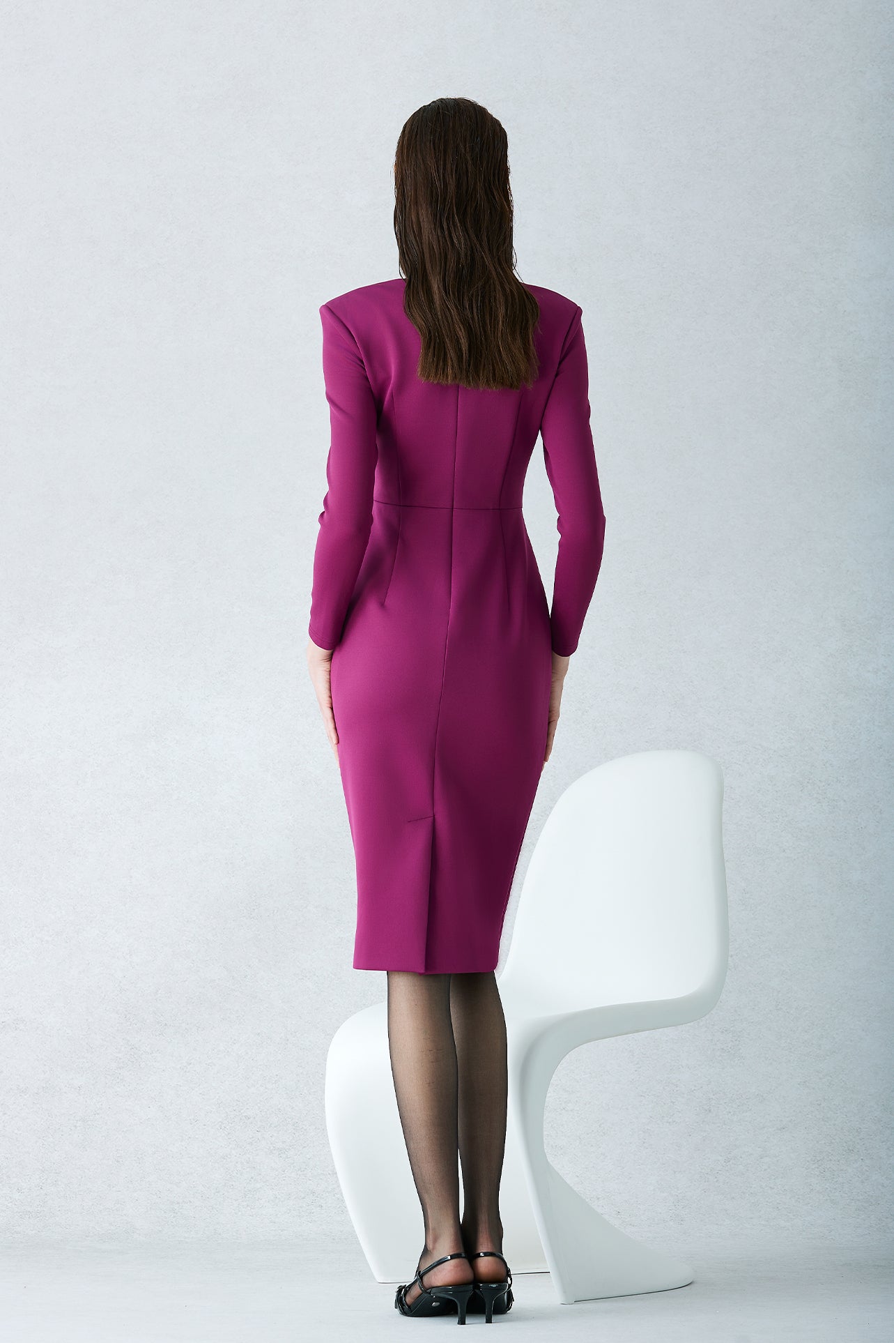 A professional woman wearing a sophisticated deep magenta long-sleeve pencil dress, featuring a unique square neckline and elegant ruched detailing at the waist for a flattering, slim-fit executive look.