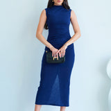 A professional woman wearing a sophisticated navy blue sleeveless midi dress, featuring an elegant high neckline and flattering ruched detailing along the side for a slim-fit executive look.