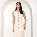 A professional woman wearing a sophisticated off-white pinstripe vest top, featuring a slim-fit tailored silhouette, classic V-neck, and contrasting black buttons for a modern business casual look.