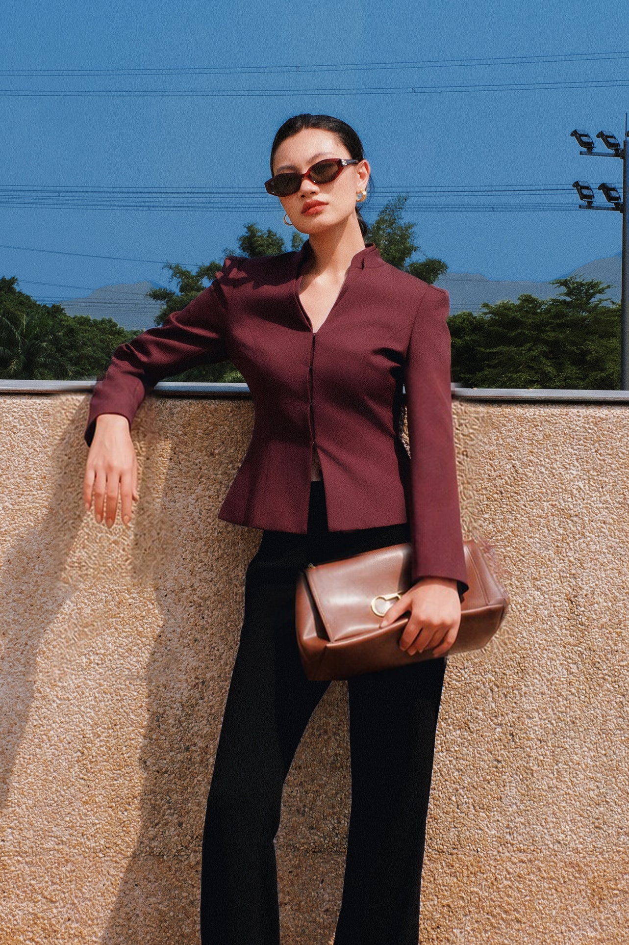 A professional Asian woman wearing glasses and an elegant deep burgundy tailored blazer featuring a sophisticated stand collar with a split V-neckline, structured shoulders, and a clean minimalist front.