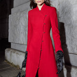 A professional woman smiling in a stunning festive red coat dress, featuring a stand-up mandarin collar with a large 3d rose ornament and an elegant side-button closure, perfect for a Christmas or holiday formal event.