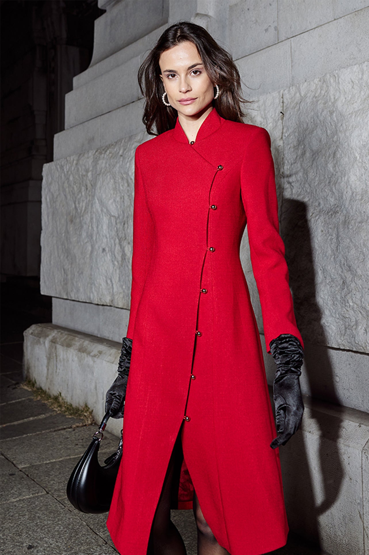 A professional woman smiling in a stunning festive red coat dress, featuring a stand-up mandarin collar with a large 3d rose ornament and an elegant side-button closure, perfect for a Christmas or holiday formal event.