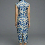 A professional woman wearing a sophisticated modern qipao dress, featuring a blue and white porcelain floral print, a mandarin collar with keyhole detail, and a slimming tailored fit for an elegant executive look.