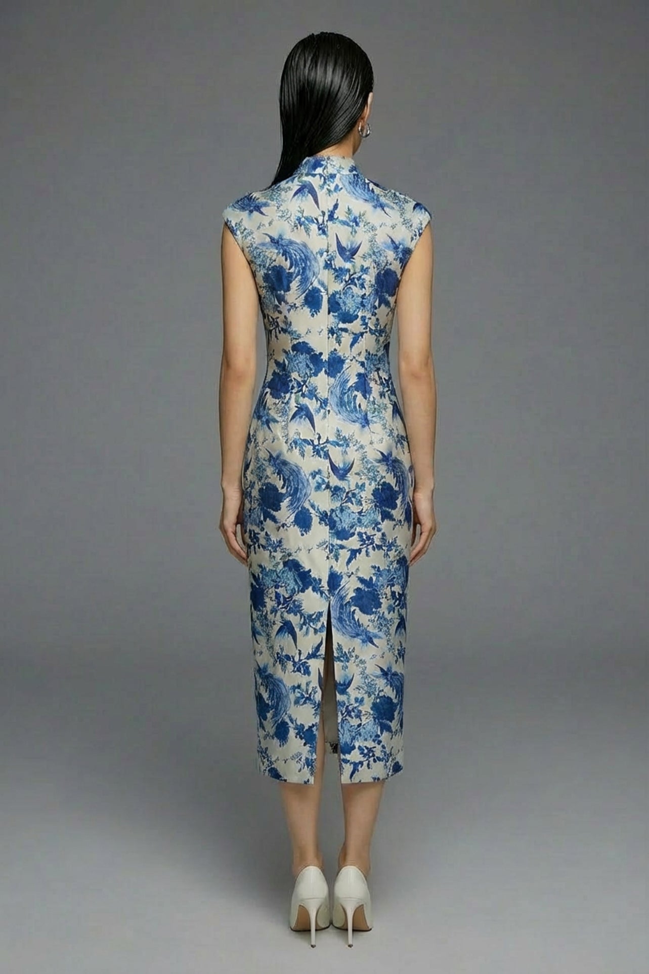 A professional woman wearing a sophisticated modern qipao dress, featuring a blue and white porcelain floral print, a mandarin collar with keyhole detail, and a slimming tailored fit for an elegant executive look.