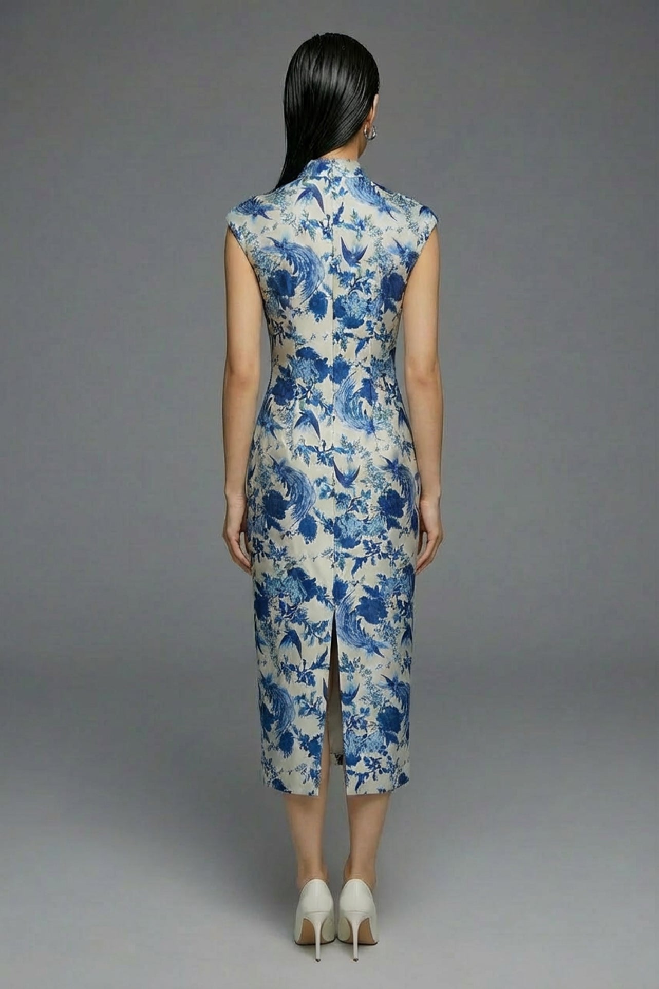A professional woman wearing a sophisticated modern qipao dress, featuring a blue and white porcelain floral print, a mandarin collar with keyhole detail, and a slimming tailored fit for an elegant executive look.