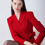 A sophisticated woman walking in London wearing an elegant vibrant red wrap coat dress, featuring a tie-waist belt and notched lapels for a polished executive street style look.