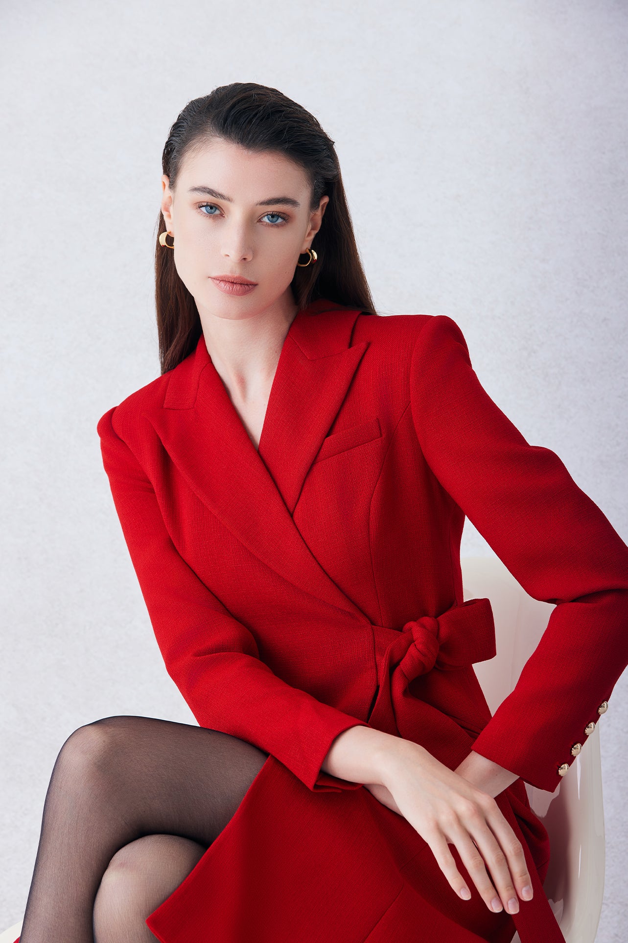 A sophisticated woman walking in London wearing an elegant vibrant red wrap coat dress, featuring a tie-waist belt and notched lapels for a polished executive street style look.