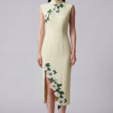 A professional woman wearing a stunning pale yellow sleeveless dress, featuring a traditional mandarin collar, exquisite white floral embroidery appliques along the neckline and hem, and an elegant side slit for a sophisticated modern oriental look.