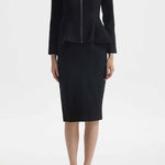 A professional woman wearing a sophisticated cream tweed skirt suit, featuring a tailored jacket with a modern front zipper and an elegant stand collar for a polished executive office look.