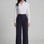 A professional woman wearing sophisticated navy blue pinstripe wide-leg trousers, featuring a high-waisted tailored fit and elegant vertical stripes for a polished executive office look.