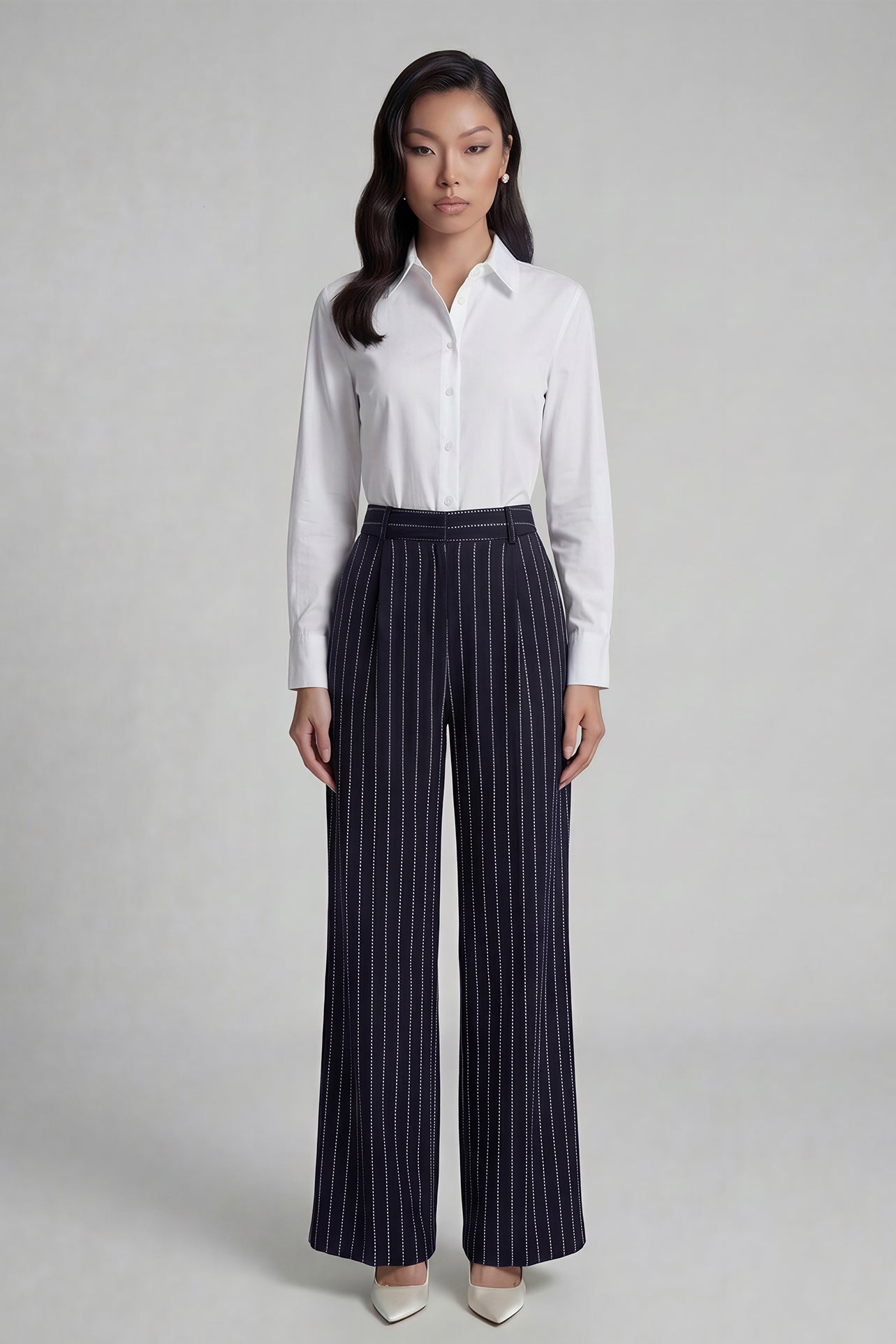 A professional woman wearing sophisticated navy blue pinstripe wide-leg trousers, featuring a high-waisted tailored fit and elegant vertical stripes for a polished executive office look.