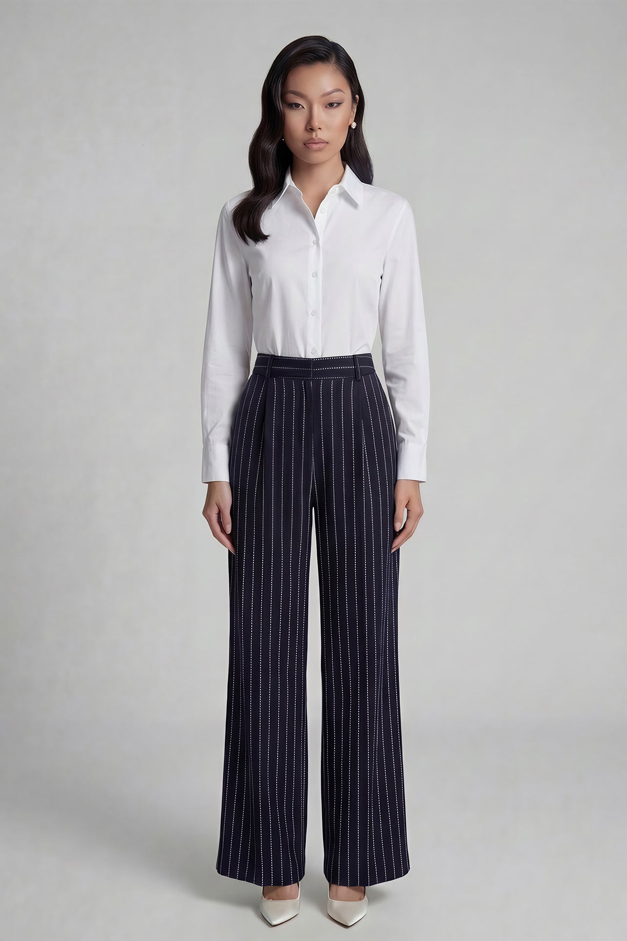 A professional woman wearing sophisticated navy blue pinstripe wide-leg trousers, featuring a high-waisted tailored fit and elegant vertical stripes for a polished executive office look.