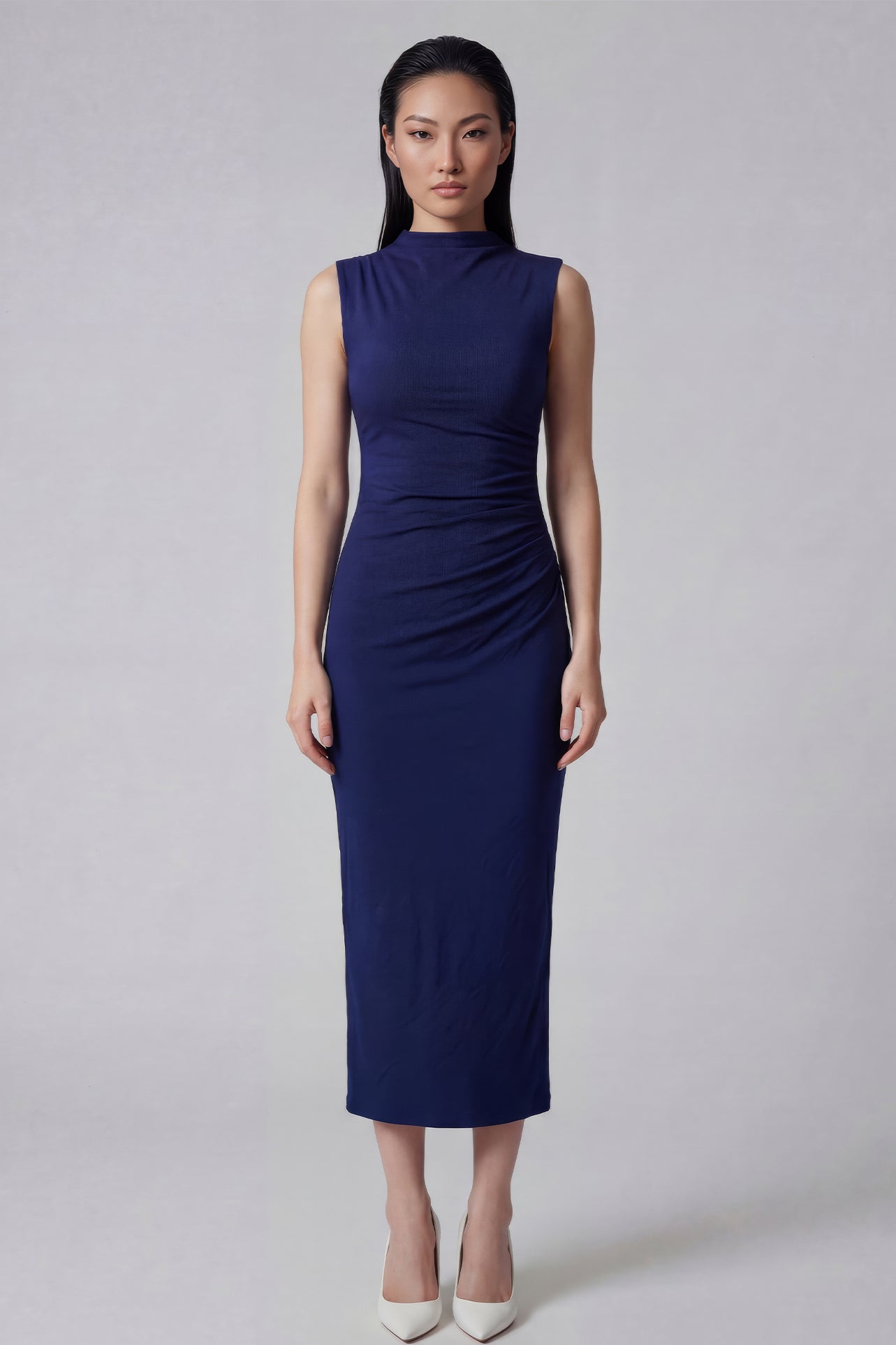 A professional woman wearing a sophisticated navy blue sleeveless midi dress, featuring an elegant high neckline and flattering ruched detailing along the side for a slim-fit executive look.