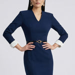 A professional woman wearing a sophisticated navy blue V-neck sheath dress, featuring elegant white contrast turn-up cuffs and a slim black belt with a gold buckle for a polished executive look.