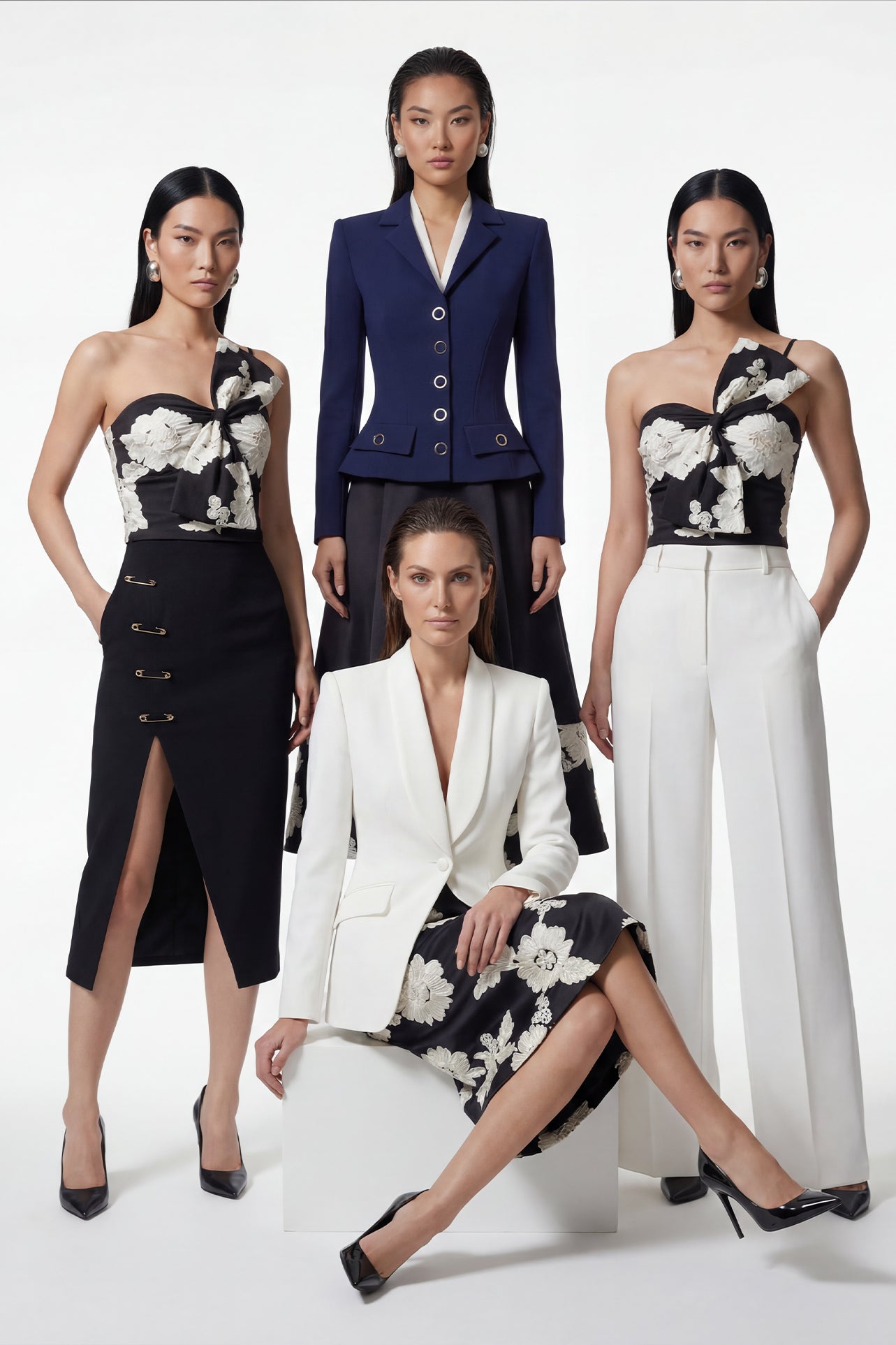 A professional woman wearing a sophisticated one-shoulder black and white floral print top, featuring a dramatic oversized bow detail on the shoulder, paired with white high-waisted trousers for an elegant evening look.