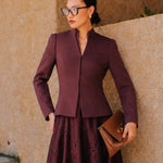 A professional Asian woman wearing glasses and an elegant deep burgundy tailored blazer featuring a sophisticated stand collar with a split V-neckline, structured shoulders, and a clean minimalist front.