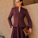 A professional Asian woman wearing glasses and an elegant deep burgundy tailored blazer featuring a sophisticated stand collar with a split V-neckline, structured shoulders, and a clean minimalist front.