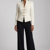 A sophisticated woman enjoying coffee in Paris wearing an elegant cream white modern qipao suit, featuring a mandarin collar blazer with traditional frog buttons and a matching pleated skirt for a quiet luxury oriental look.