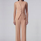 A professional woman wearing sophisticated apricot-colored high-waisted straight-leg trousers, featuring a unique pointed waistband design for a tailored executive office look.