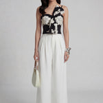 A professional woman wearing sophisticated black high-waisted wide-leg trousers, featuring a flattering high-rise fit and a flowing full-length silhouette for an elegant office look.