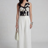 A professional woman wearing sophisticated black high-waisted wide-leg trousers, featuring a flattering high-rise fit and a flowing full-length silhouette for an elegant office look.