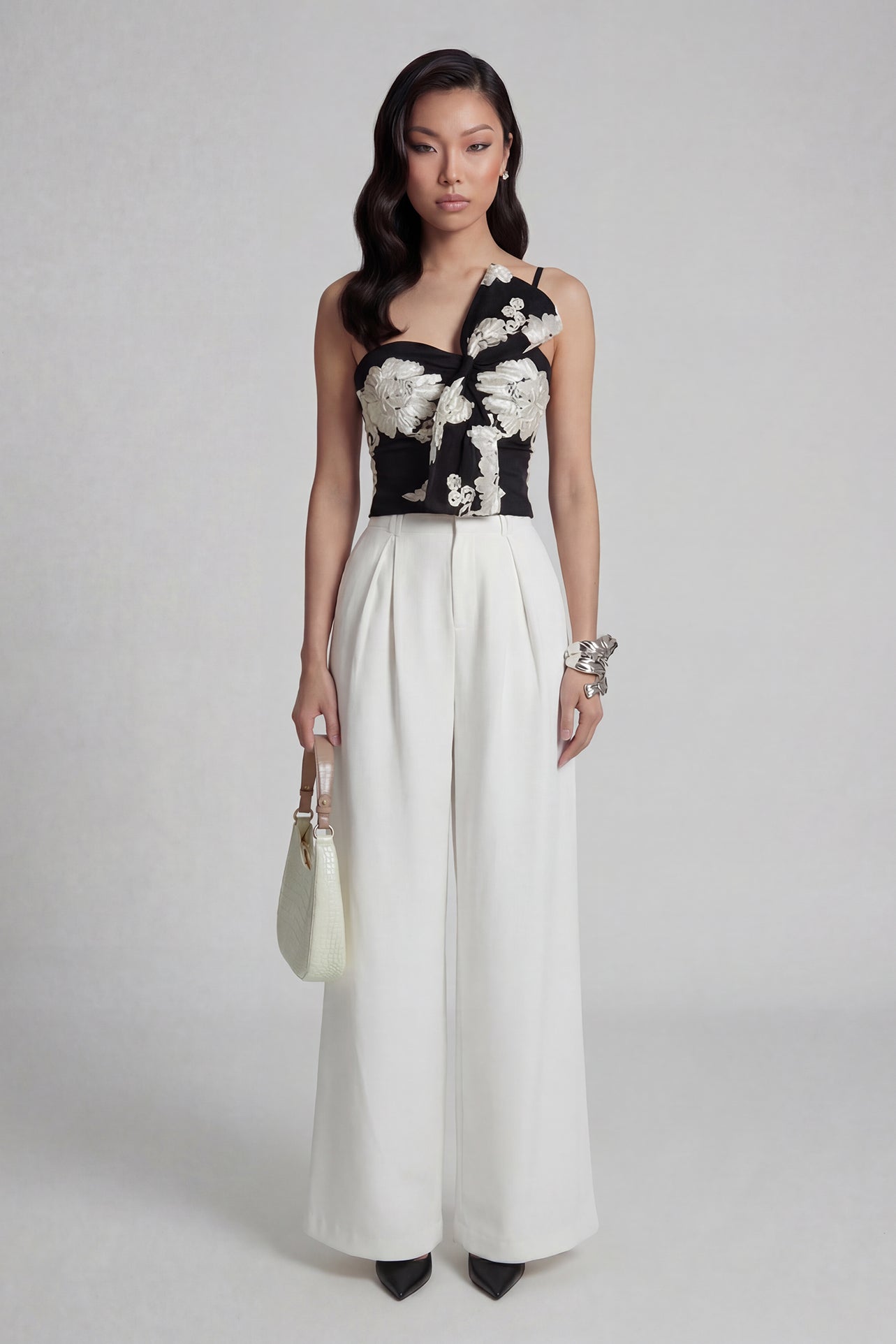 A professional woman wearing sophisticated black high-waisted wide-leg trousers, featuring a flattering high-rise fit and a flowing full-length silhouette for an elegant office look.