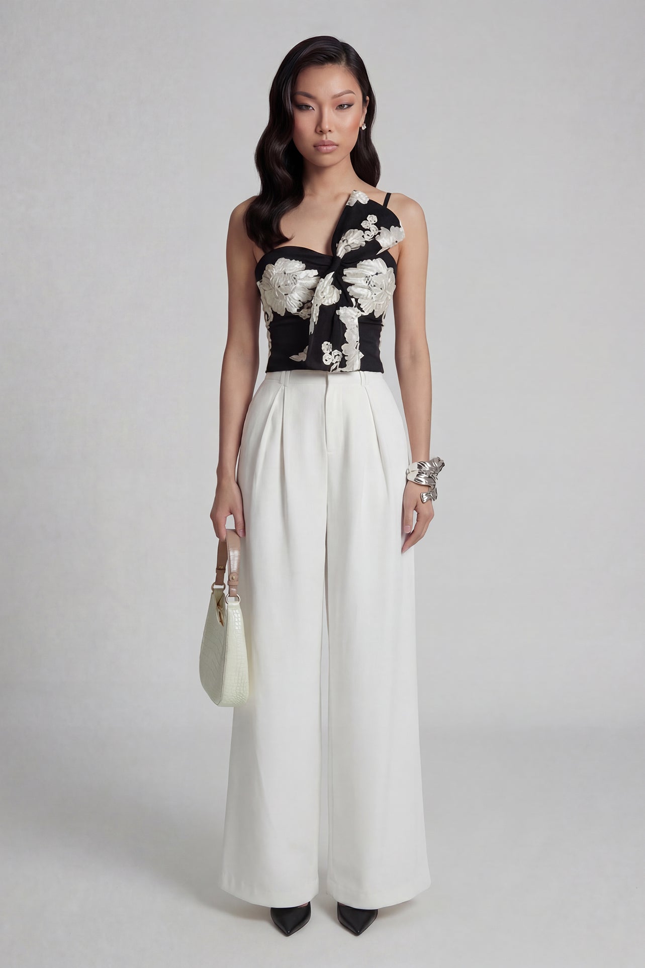 A professional woman wearing sophisticated black high-waisted wide-leg trousers, featuring a flattering high-rise fit and a flowing full-length silhouette for an elegant office look.