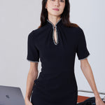 An elegant woman wearing a sophisticated black short-sleeve sheath dress, featuring a traditional mandarin collar with a modern keyhole neckline and delicate beaded trim details for a polished formal look.