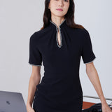 An elegant woman wearing a sophisticated black short-sleeve sheath dress, featuring a traditional mandarin collar with a modern keyhole neckline and delicate beaded trim details for a polished formal look.