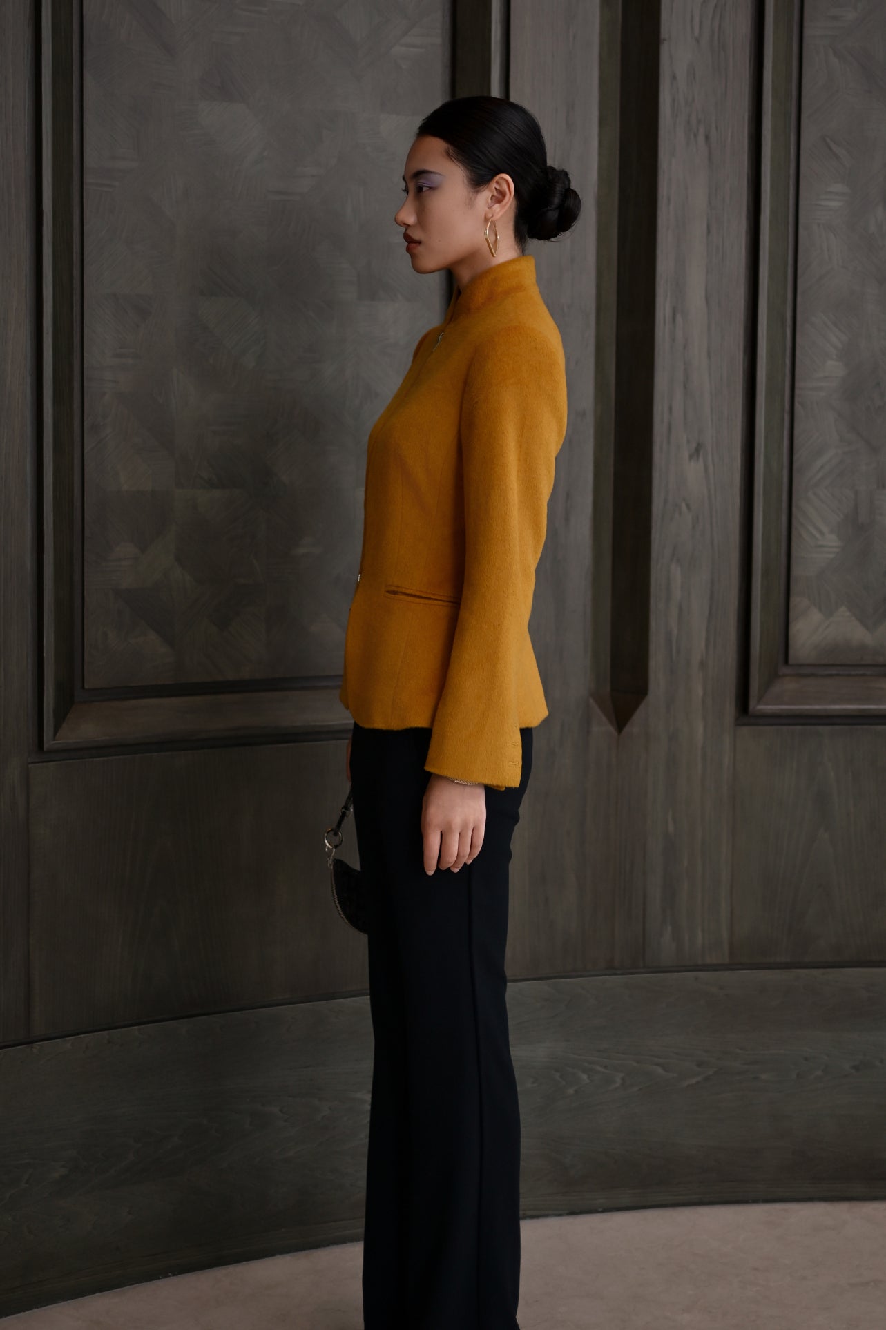 A chic professional Asian woman wearing a luxurious camel wool tailored jacket featuring a sleek stand collar, exposed two-way front zipper, structured shoulders, and an hourglass silhouette paired with a matching skirt.