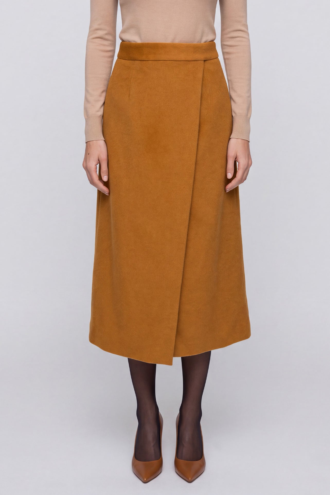 An elegant Asian woman posing in a luxurious camel wool two-piece suit featuring a sleeveless double-breasted longline vest cinched with a wide black belt, paired with a matching midi column skirt and black opera gloves.