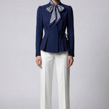 A professional woman wearing a sophisticated navy blue blazer, featuring an elegant pussy-bow neck tie, a flattering tie-waist wrap design, and subtle puff sleeves for a polished executive look.