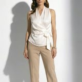 A professional woman modeling elegant satin halter wrap tops in crisp white and deep purple, featuring a sophisticated side bow tie and paired with white high-waisted trousers and a button-front skirt.