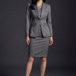 A professional woman wearing a sophisticated grey slim-fit blazer with a single gold button, featuring a tailored waist and notched lapels for an elegant executive office look.