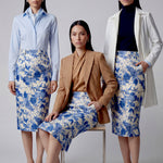 An elegant professional woman wearing a high-waisted pencil skirt featuring a sophisticated blue and white floral porcelain-style print, perfect for a polished office look.
