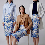 An elegant professional woman wearing a high-waisted pencil skirt featuring a sophisticated blue and white floral porcelain-style print, perfect for a polished office look.