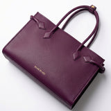 A sophisticated plum purple tote bag crafted from premium pebbled leather, displayed next to a matching shade of luxury lipstick, representing an elegant executive fashion set.