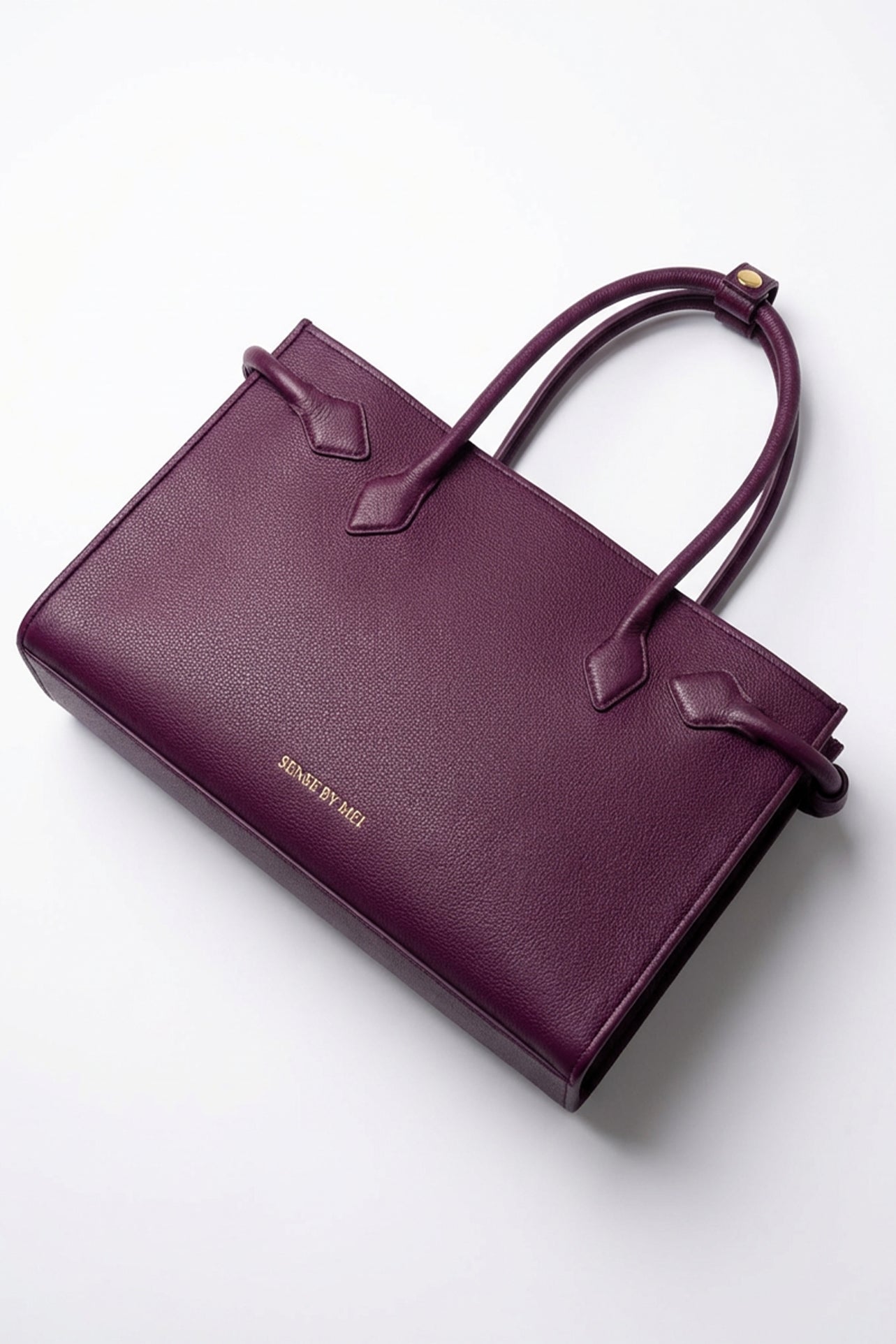 A sophisticated plum purple tote bag crafted from premium pebbled leather, displayed next to a matching shade of luxury lipstick, representing an elegant executive fashion set.