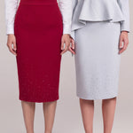 A style comparison of two elegant women's high-waisted pencil midi skirts featuring a delicate gradient of sparkling rhinestones at the hemline; shown on the left in deep red paired with a white shirt, and on the right in pale ice-blue paired with a matching peplum top.