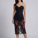 An elegant woman wearing a sophisticated black floral lace midi skirt, featuring a sexy sheer lace overlay with a delicate scalloped hem and a tailored slim fit for a formal evening look.