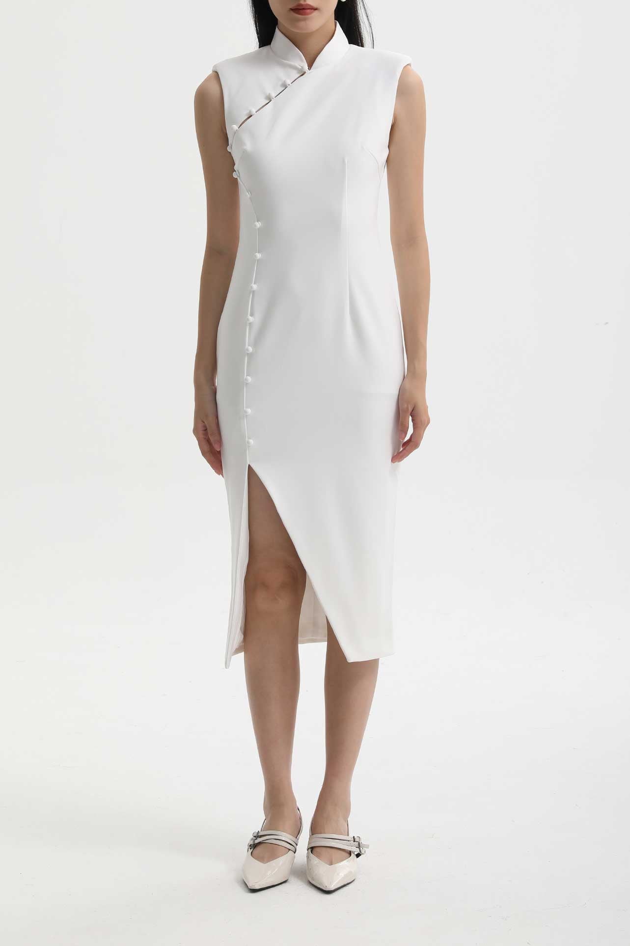 Model wearing a minimalist sleeveless modern Qipao dress featuring a mandarin collar, asymmetric side buttons, and a high thigh slit.